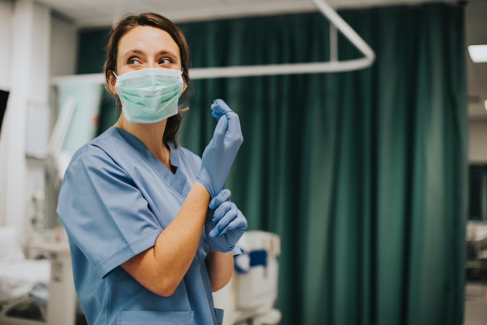 nurse in a mask putting on gloves