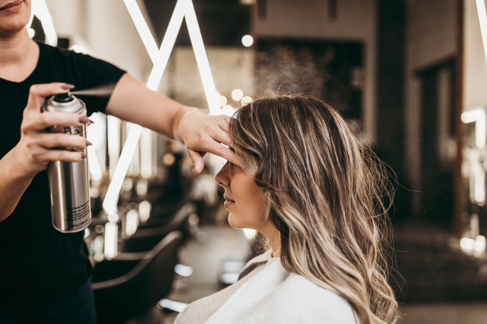 hairdresser using hairspray on a client